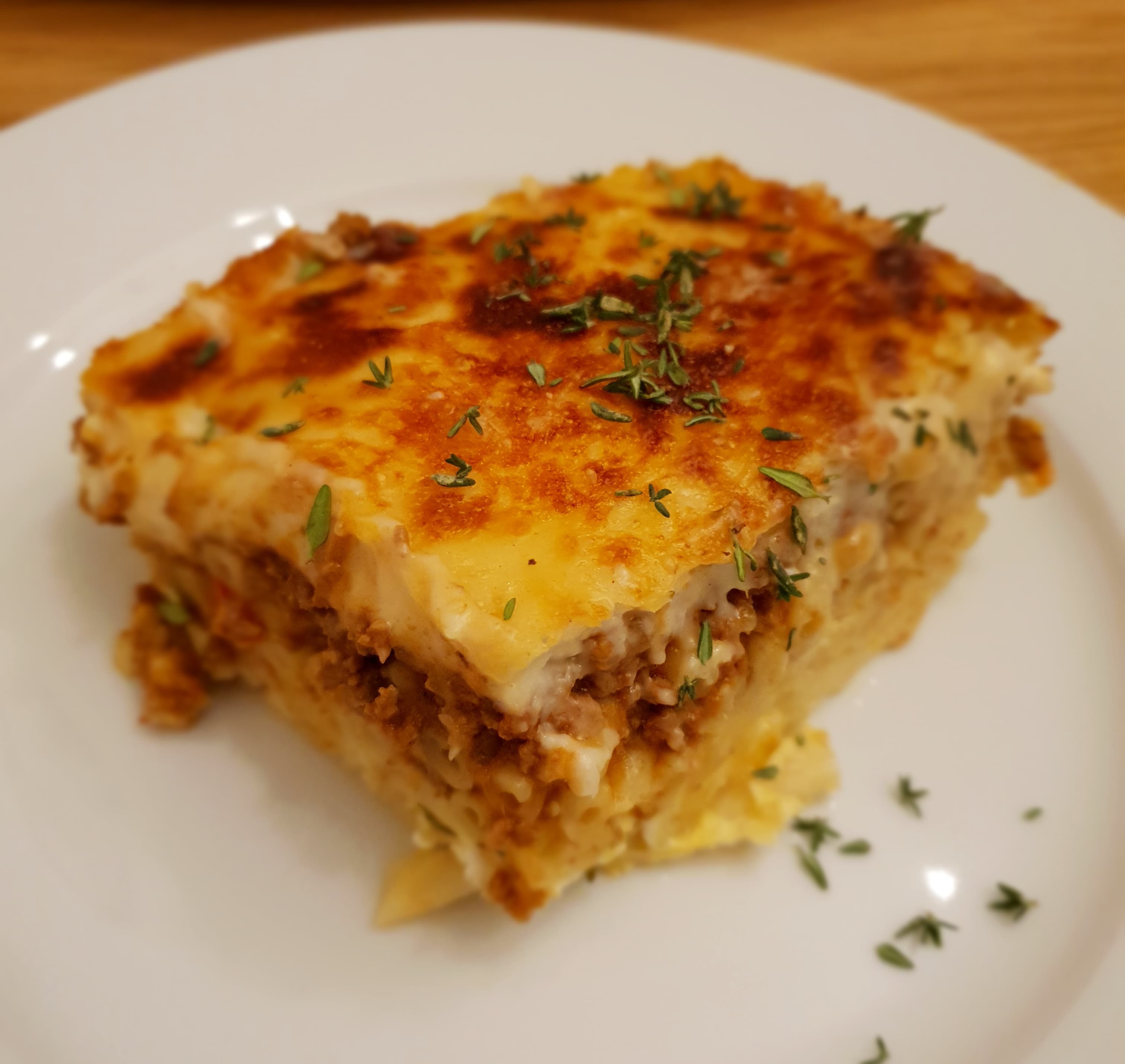 Slice of Greek pastitsio showing layers of pasta meat and bechamel