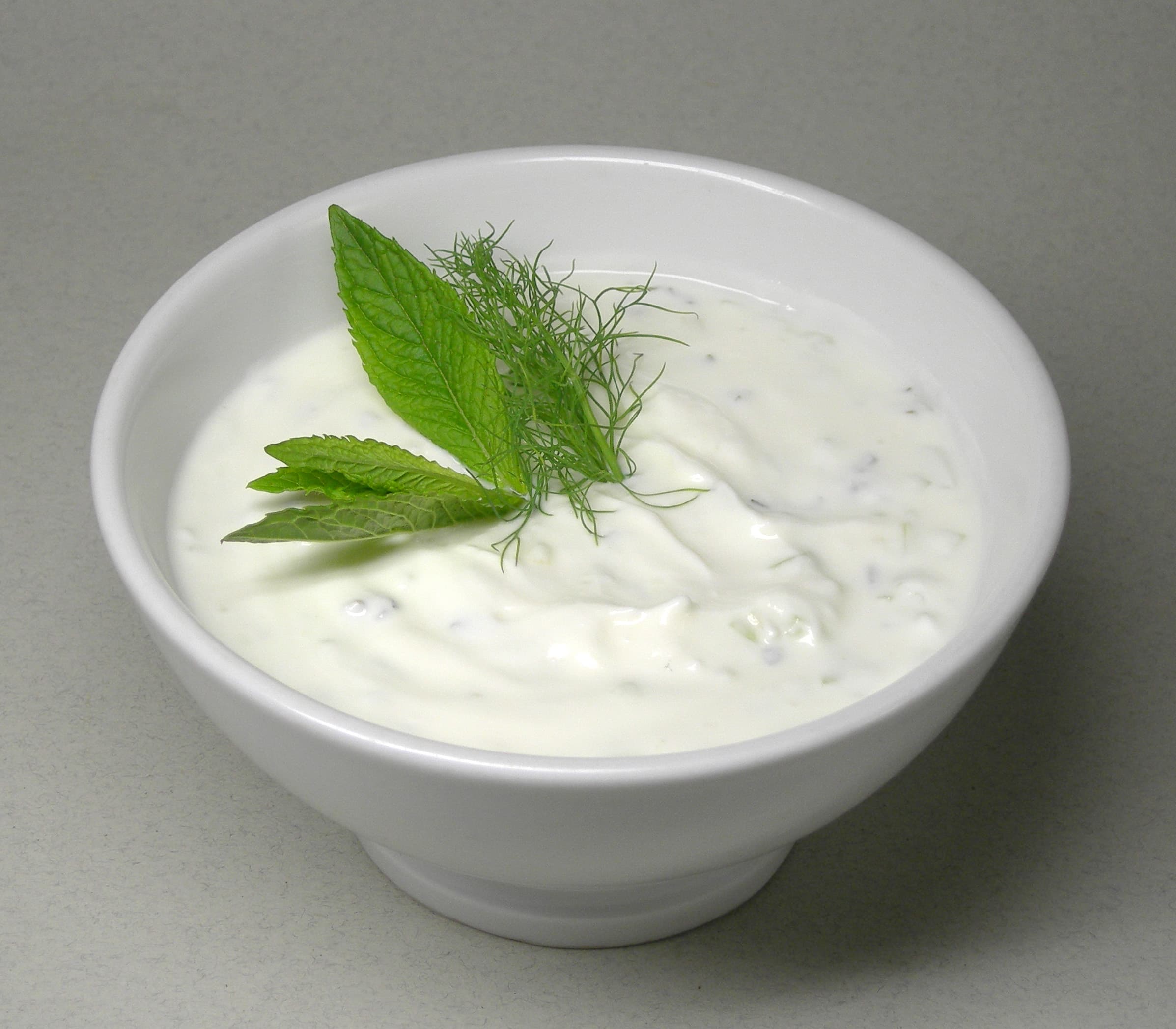 Creamy tzatziki sauce in a bowl with cucumber and dill garnish