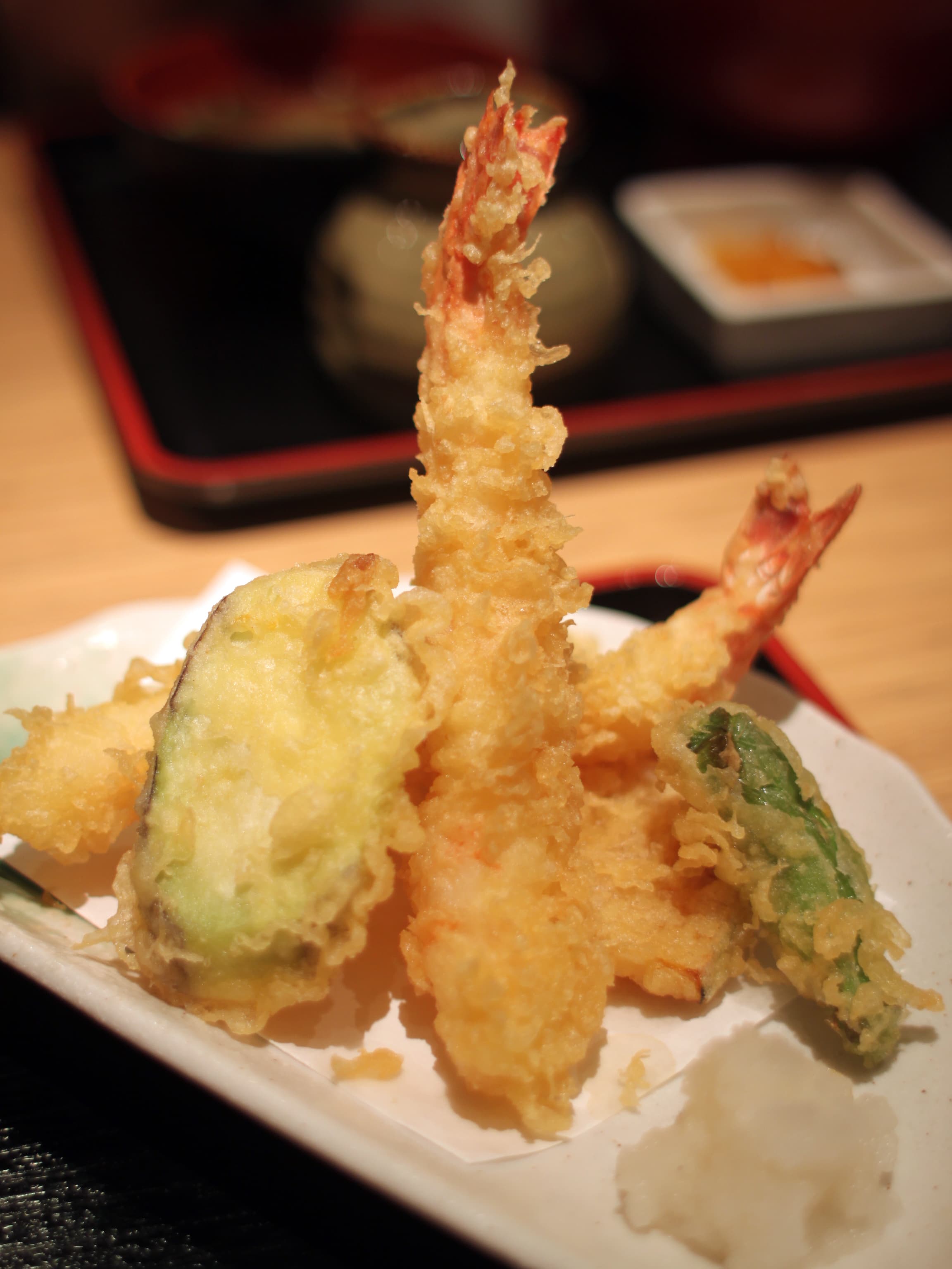 Assorted vegetable tempura arranged on a plate with dipping sauce