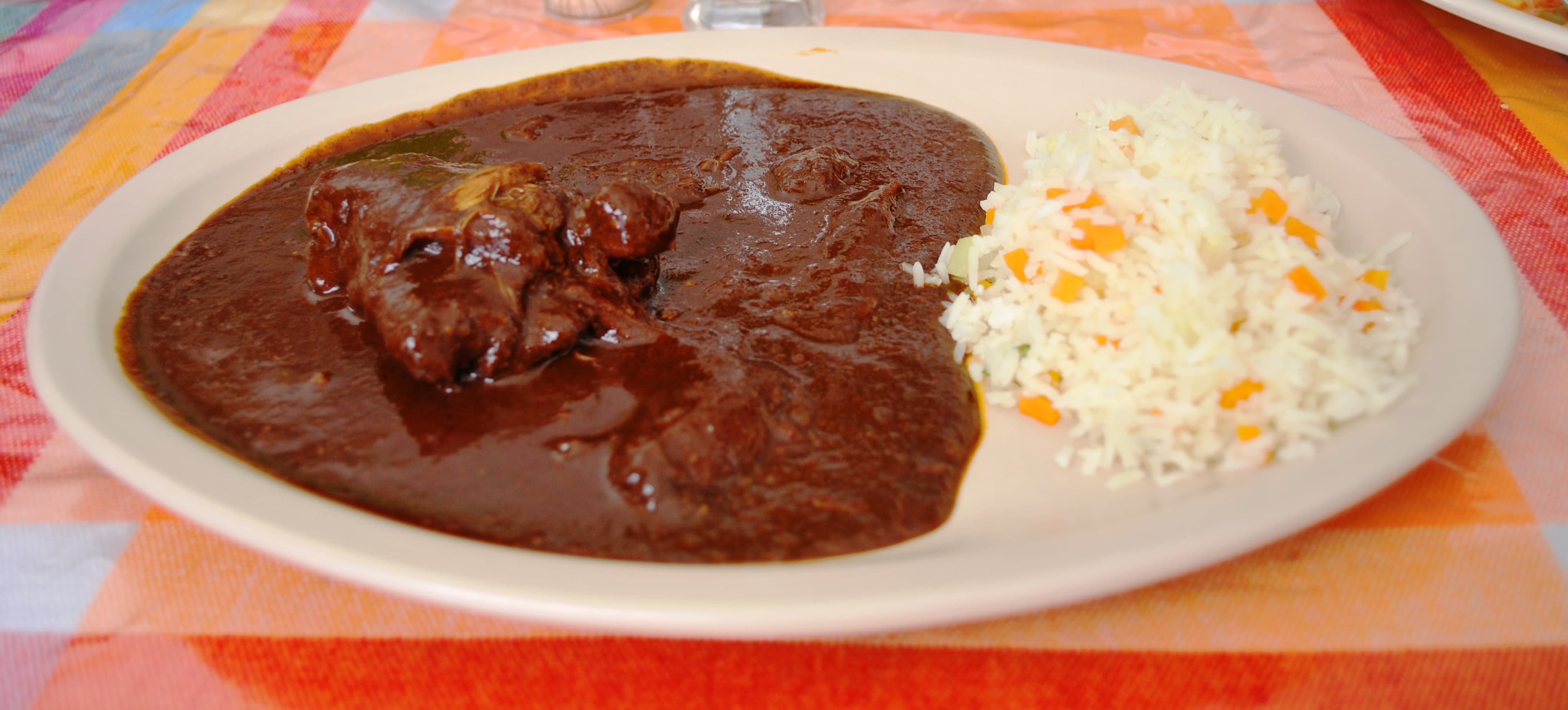 Rich mole sauce being poured over enchiladas