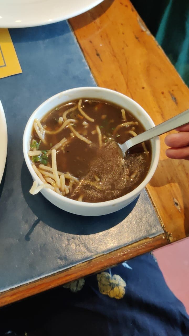 Bowl of spicy tortilla soup topped with crispy tortilla strips, avocado, and lime