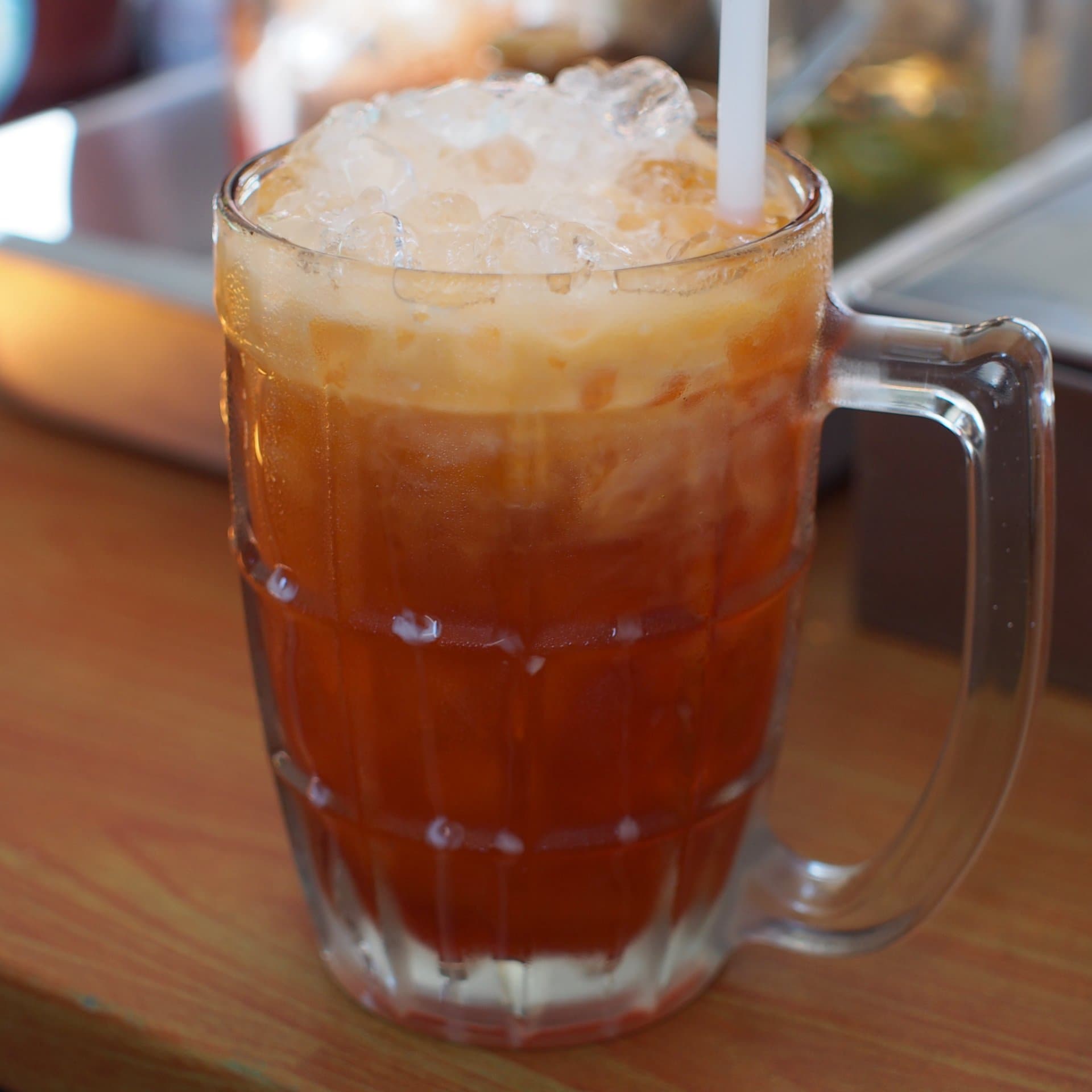 Tall glass of orange Thai iced tea with cream swirl