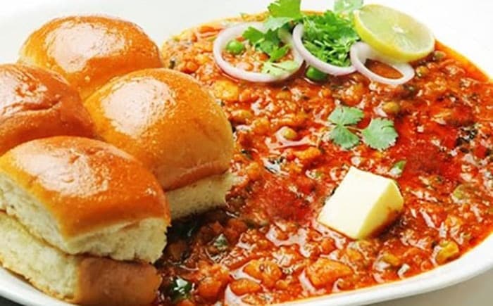 Pav bhaji with buttered toasted rolls and onion garnish