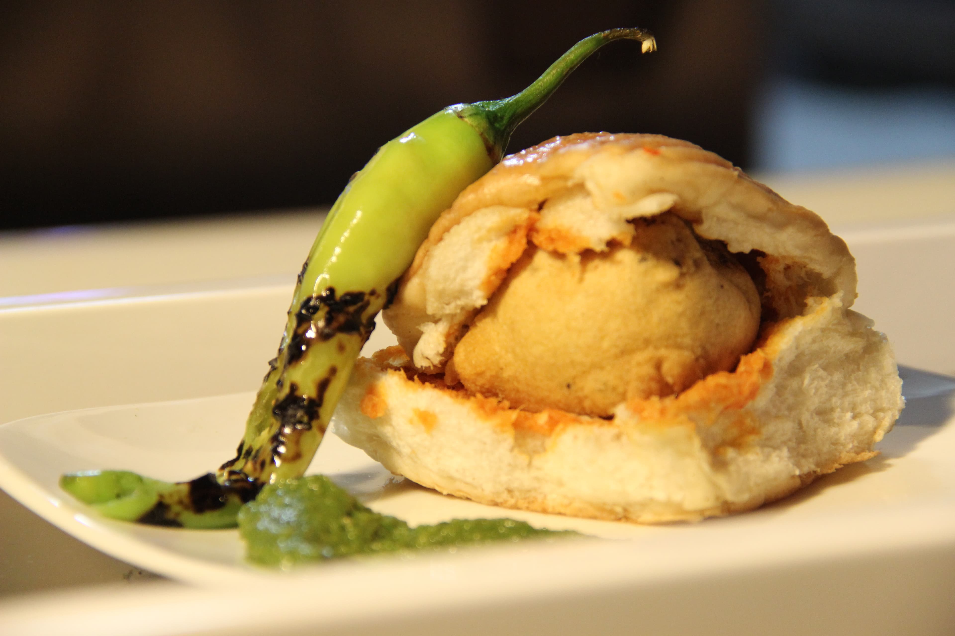 Vada pav with crispy potato fritter, green chutney, and bread roll