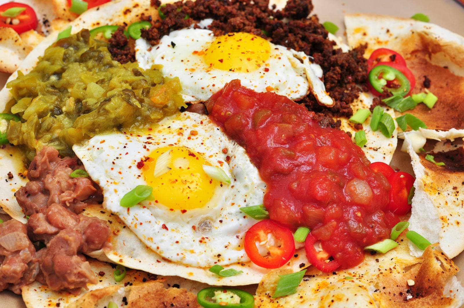 Huevos rancheros with fried eggs, ranchero sauce, and avocado on a colorful plate