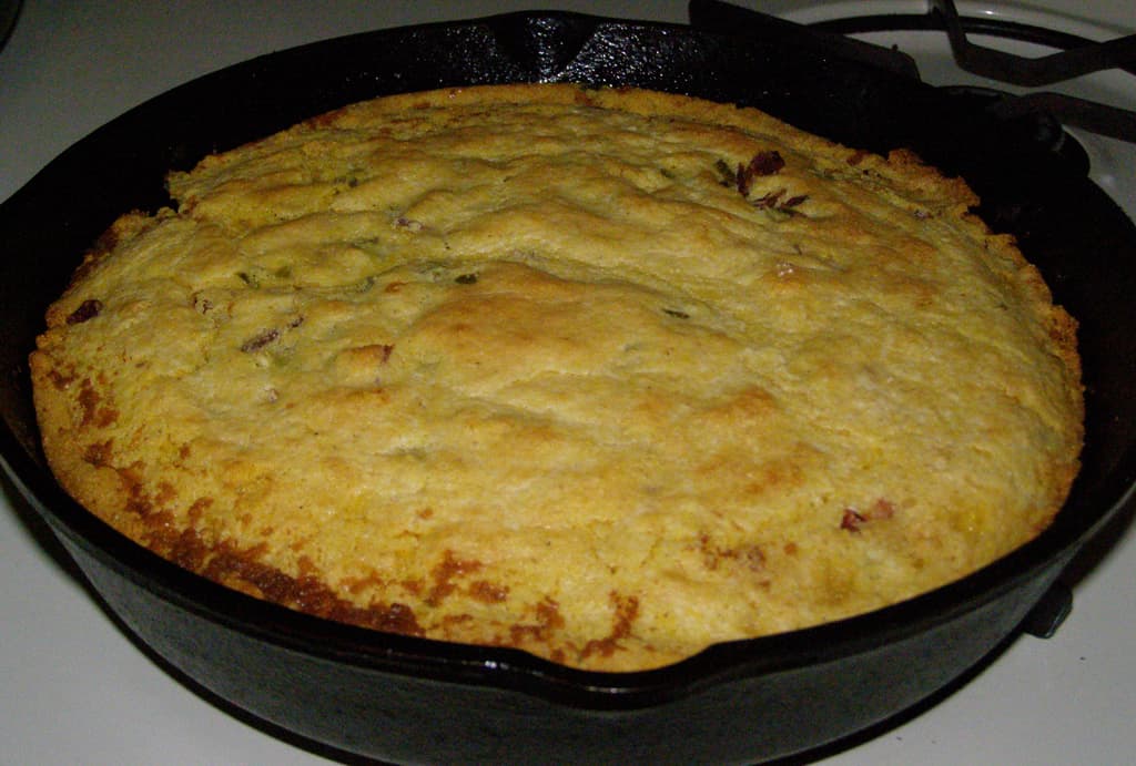 Jalapeño cheddar cornbread in a cast iron skillet with melted cheese