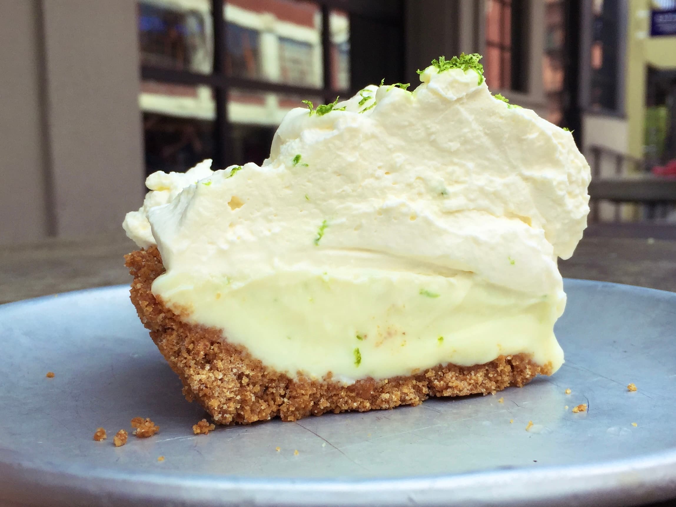 Key lime pie with whipped cream topping and lime slices on a white plate