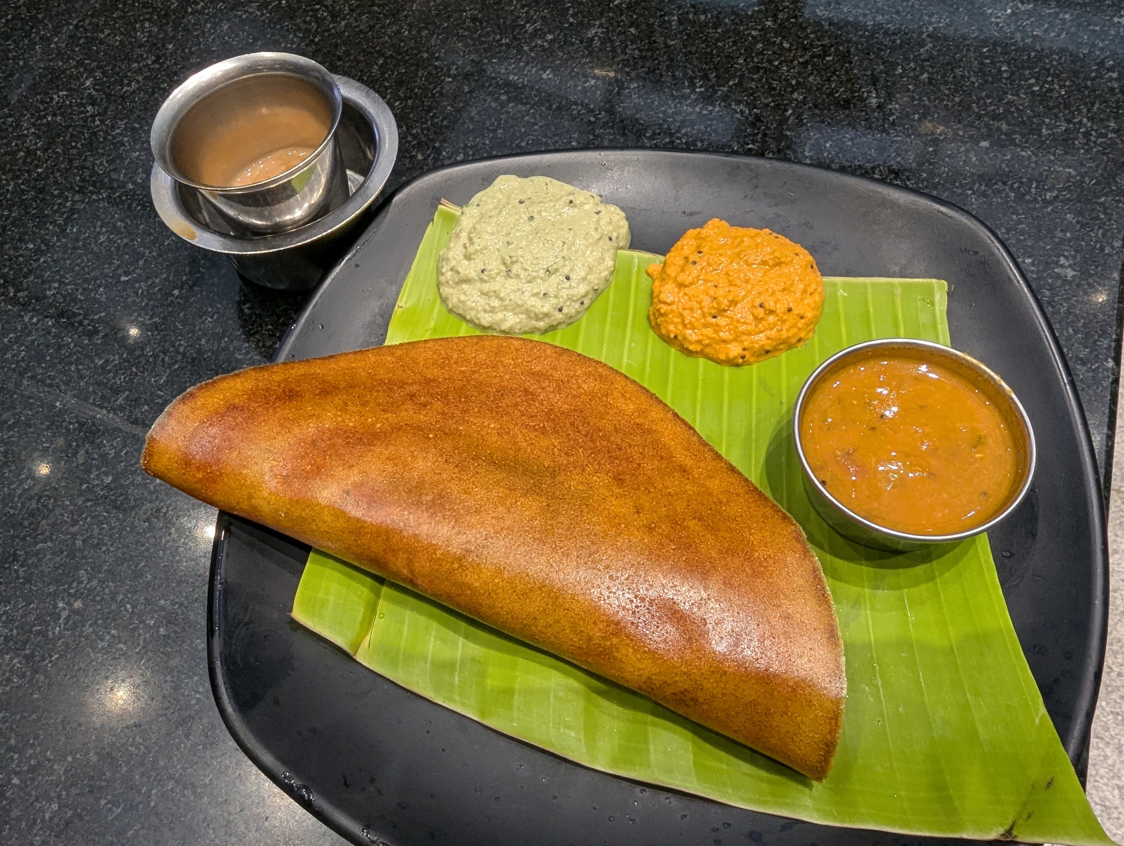 Golden masala dosa with potato filling on a banana leaf