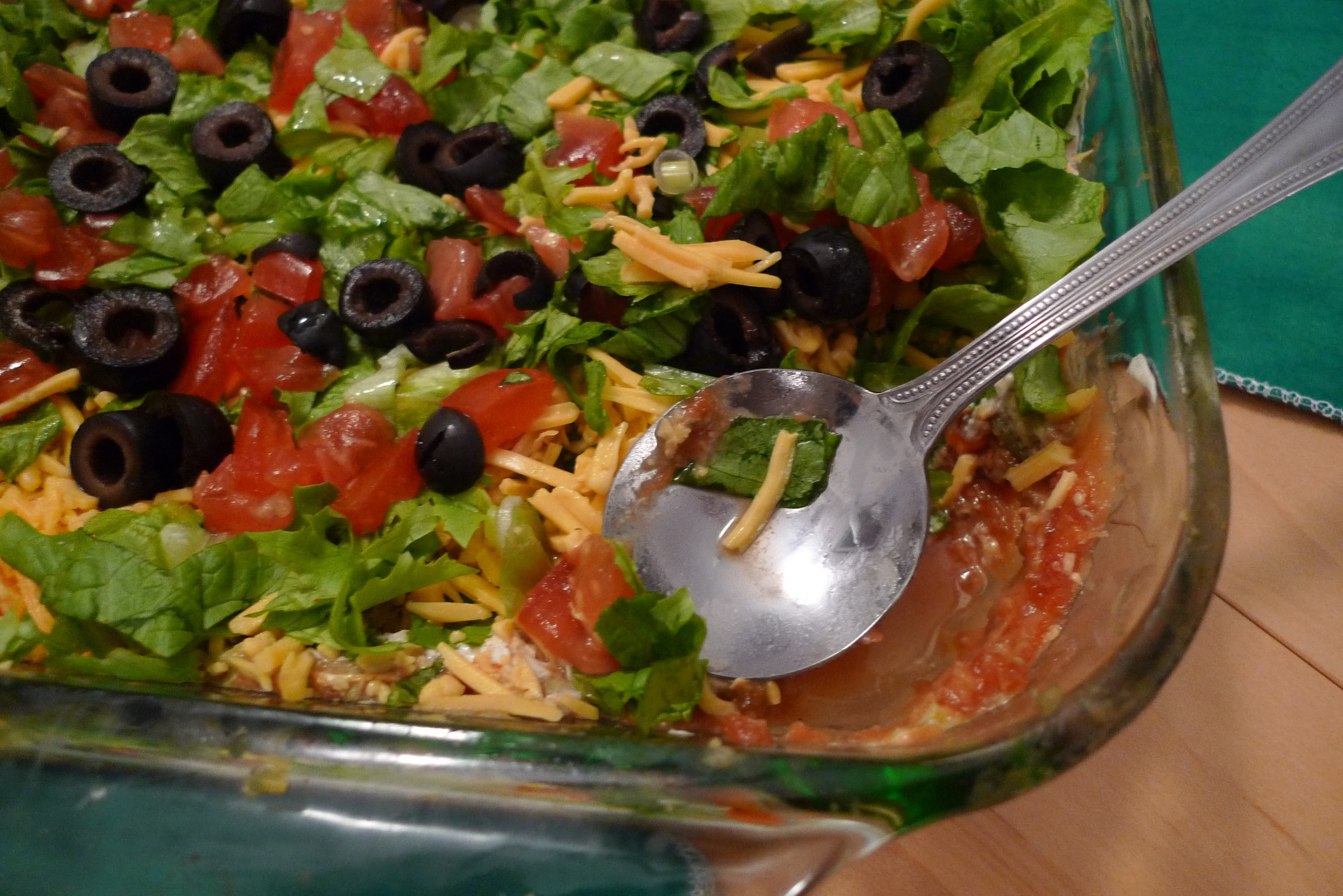 Seven layer dip in a glass dish showing colorful layers