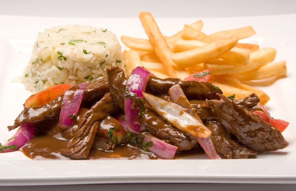 Peruvian lomo saltado with beef, tomatoes, and fries over rice