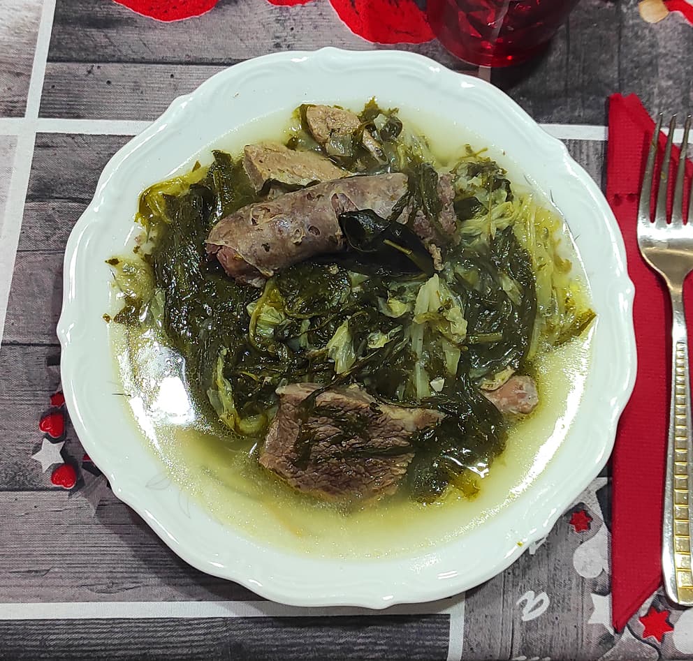 Bowl of Italian wedding soup with mini meatballs, pasta, and greens