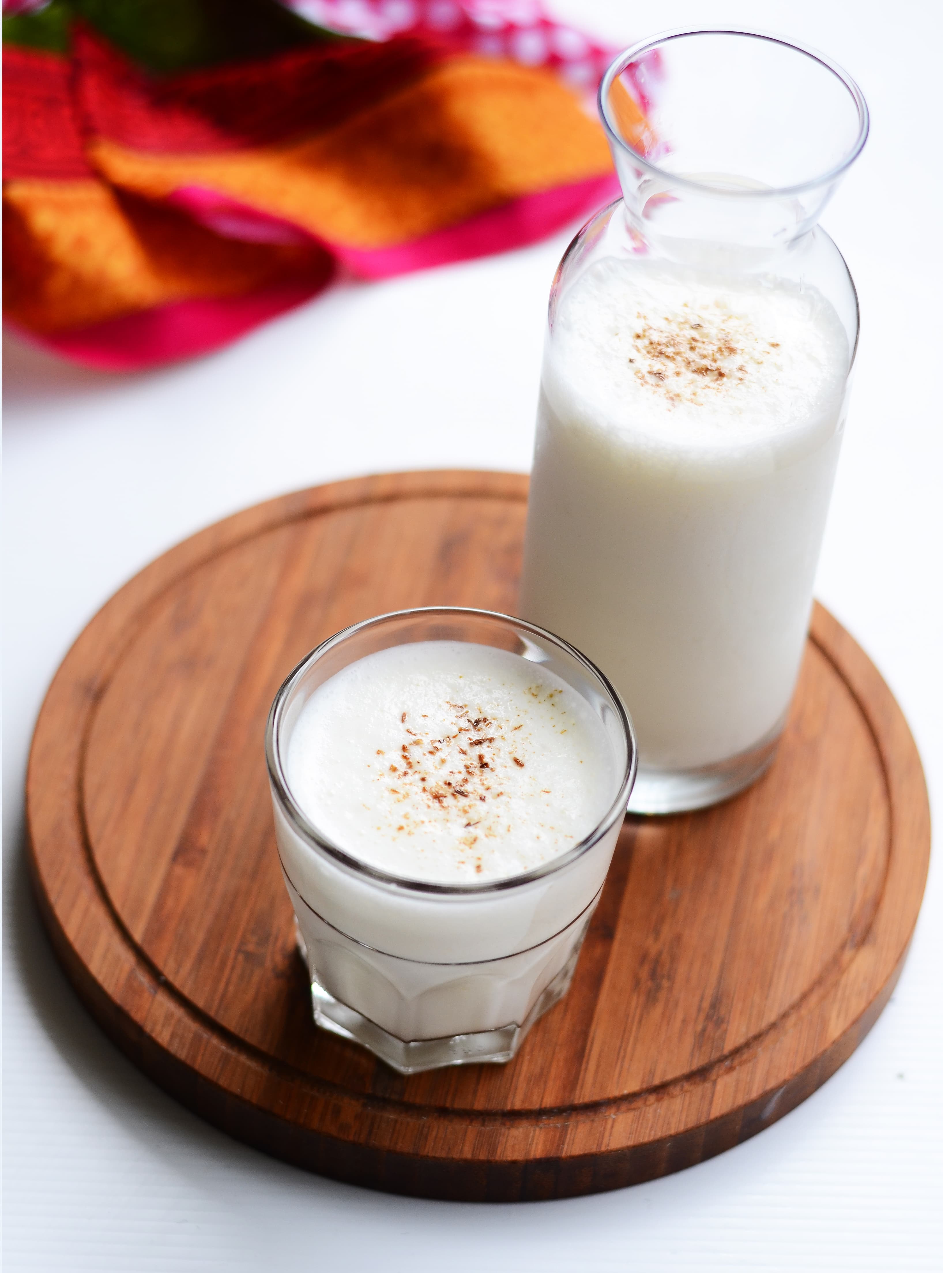 Tall glass of golden mango lassi with a cardamom garnish