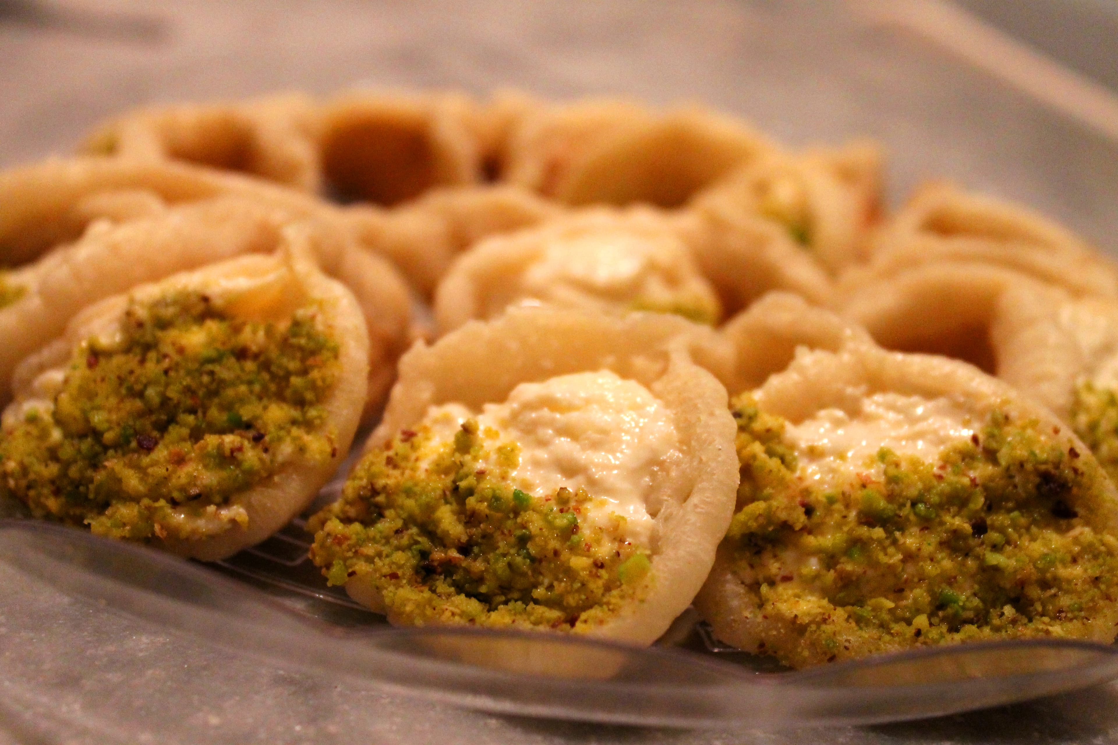 Golden fried qatayef stuffed pancakes with syrup and pistachios